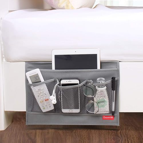 DuomiW bedside caddy mounted on a bed with a remote control, mobile phone, glasses, and a pen in the mesh front pockets and a tablet in the rear pocket