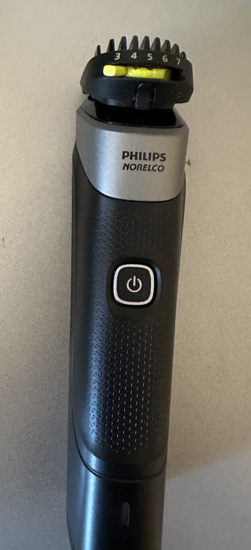 Philips Norelco Multigroom 5000 in use showing trimmer head detail and 18-piece kit